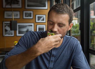 Young happy man eating his lunch. Handsome man enjoying his organic food. Healthy eating