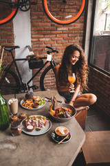 Woman enjoying fresh organic vegetarian food and glass of kombucha in hipster style cafe with bicycle design