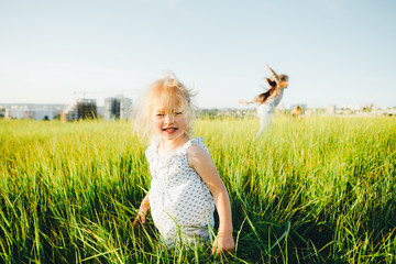 Children playing catch-up in the green field at sunset.