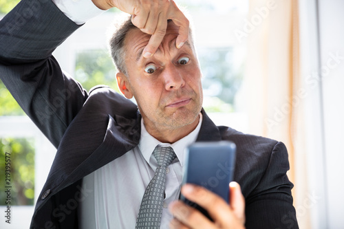 Cuadros en Lienzo Terrified Businessman Looking At Mobile Phone Screen
