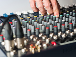 Dj adjusting buttons on audio mixer