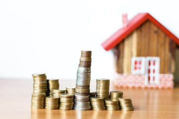 Real estate or property investment concept. coin stack with house model on table.