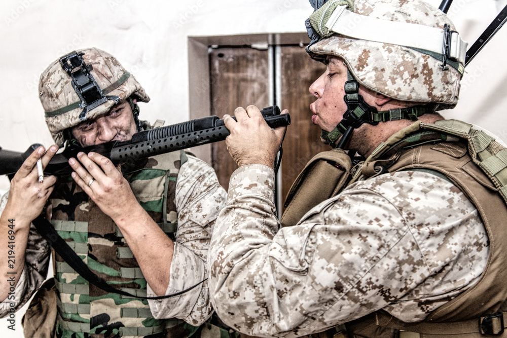 Army soldier blowing cigarette smoke in combat shotgun chamber while his  comrade inhaling smoke from gun barrel. United States Marine Corps  infantries smoking marijuana with service pump-action rifle Stock Photo