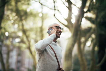 Wall Mural - Businessman walking on street to office while talking on cell ph