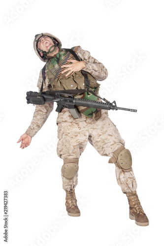 Fotografía Studio shoot of army soldier in combat uniform and body armor, screaming, clutching chest, dropping weapons and falling down after being fatally shot in military firefight