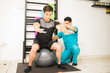 © AntonioDiaz - Physiotherapist Helping Man Balancing On Exercise Ball