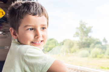 cute cheerful boy goes to rest on the train