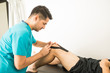 © AntonioDiaz - Physiotherapy Professional Applying KT Tape On Athlete's Knee