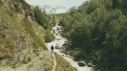 Wall Mural - mountain tourist walking along rapid river back view. hiking mountain