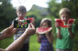 © olsima - Female hands taking photo of cheerful happy children eating watermelon