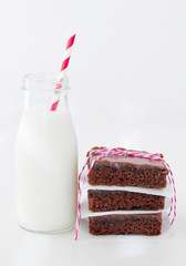 Photograph of three slices of Texas Sheet Cake stacked next to a bottle of milk with a straw