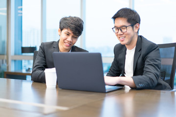 2 businessmen are working seriously with a laptop computer.