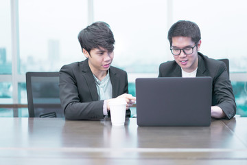 2 businessmen are working seriously with a laptop computer.