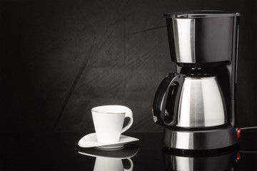 Coffee machine with pot and cup on the black mirror background