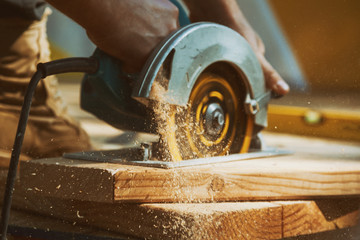 close-up of a carpenter using a circular saw to cut a large board of wood