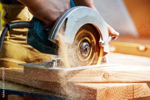 Fotografía Building contractor worker using hand held worm drive circular saw to cut boards