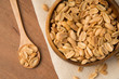 Roasted peanuts in wooden bowl and spoon putting on linen and wooden background.
