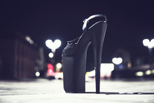 Extremely High Heeled Fetish Shoes, One Black Shoe Stands On The Asphalt On The Road In The City.