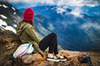 © Jordan - a woman sitting on the top of a mountain looking down at the forest valley below