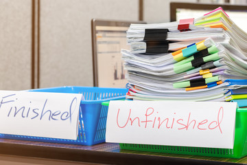 Pile of unfinished document on office desk. Stack of homework assignment archive with colorful paper and paper clip on teacher's table waiting to be managed and checked. Education and business concept