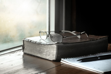 Sticker - Holy Bible with eye glasses and notebook, pen on wooden table with window light in the morning.