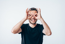 Young Creative Man Holding Fingers Near Eyes Like Glasses