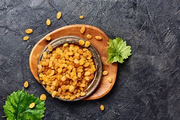 Wall Mural - Yellow raisins on black concrete background. Top view of dried grapes.