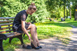 © Stanislav Ostranitsa - Beautiful young woman in a black dress re-shoes her shoes in the park