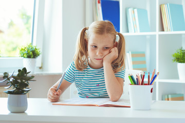 Canvas Print - Portrait of tired little schoolgirl at the table in classroom