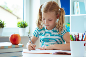 Portrait of schoolgirl at classroom writing at the table