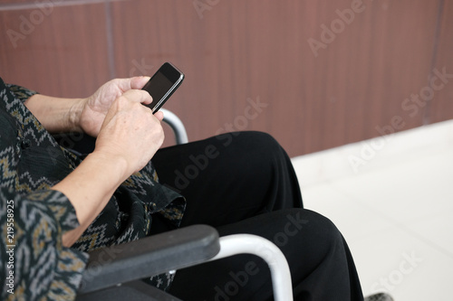 Fotografía elder woman on wheelchair holding mobile phone