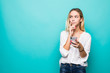 © F8  \ Suport Ukraine - Portrait of a thinking young woman using mobile phone isolated over blue background