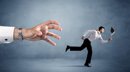 Wall Mural - Young miniature businessman running from a big hand 