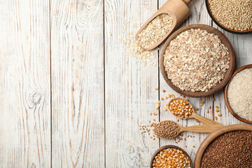 Flat lay composition with different types of grains and cereals on wooden background