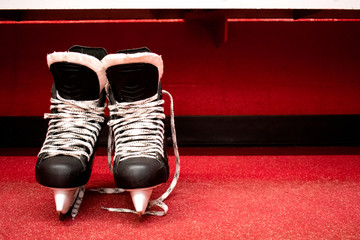 Wall Mural - Hockey skates in locker room with copy space in red background 