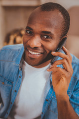 Happiness inside me. Cheerful afro-american man talking on the phone and smiling