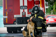 Photo Of Fireman Squatting Next To Service Dog Near Fire Engine
