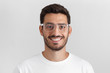 © Damir Khabirov - Close up daylight shot of smiling bearded man in white t-shirt and trendy trasparent eyeglasses, isolated on gray background