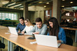 © Aleksandr - Group of college students studying in the school library, a girl and a boy are using a laptop and connecting to internet