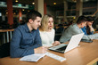 © Aleksandr - Group of college students studying in the school library, a girl and a boy are using a laptop and connecting to internet