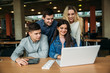 © Aleksandr - Group of college students studying in the school library, a girl and a boy are using a laptop and connecting to internet