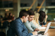© Aleksandr - Group of college students studying in the school library, a girl and a boy are using a laptop and connecting to internet