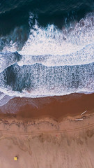 Abstract drone shot, looking down on Durban's south beach as two canoes are carried passed