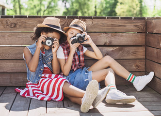 Wall Mural - Beautiful little girls taking pictures with photocameras. Cute smilling happy girls playing outdoors