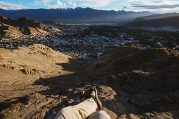 Wall Mural - travelling in leh city, in ladakh, india. a man sitting on cliff enjoying leh city view in the morni
