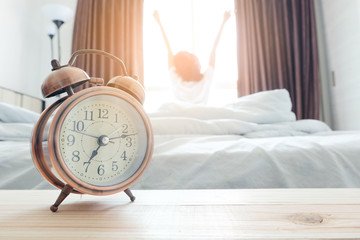 alarm clock . background happy woman stretching in bed after waking up, sunlight in morning.