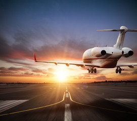 Private jet plane landing on runway in beautiful sunset light.