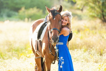 Beautiful blonde girl is walking with a horse