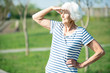 © Seventyfour - Waist up portrait of active senior woman looking away shielding eyes from sunlight outdoors, copy space