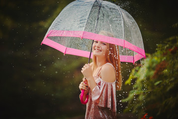 Happy beautiful girl with an umbrella in the rain during a fores